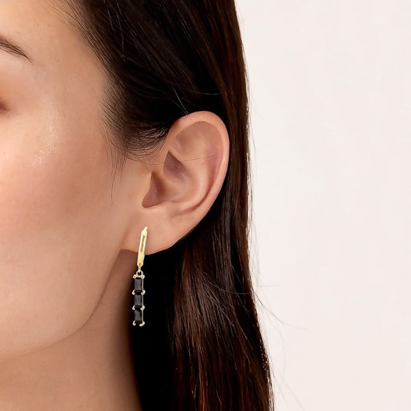 Woman wearing gold black triple baguette bar drop hoop earrings