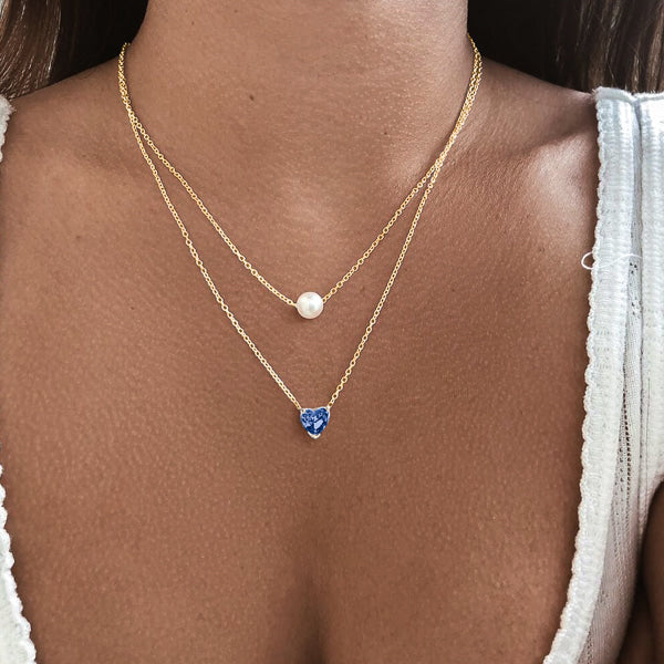 Woman wearing a gold blue crystal heart necklace