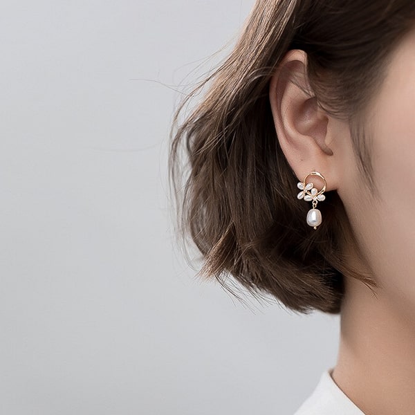 Woman wearing gold circle pearl drop stud earrings