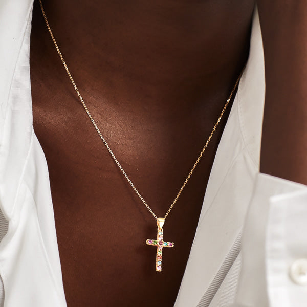 Woman wearing a colorful crystal cross on a golden necklace