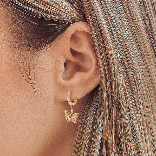 Woman wearing gold crystal butterfly drop hoop earrings