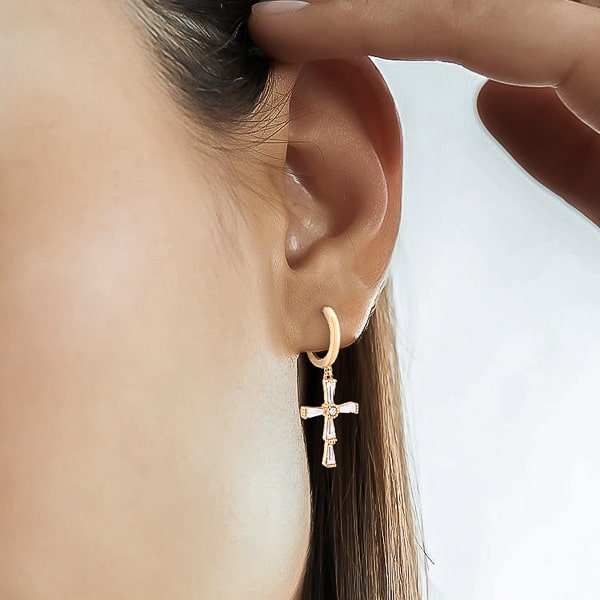 Woman wearing gold crystal cross hoop earrings