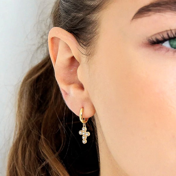 Woman wearing gold crystal cross mini hoop earrings