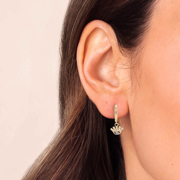 Woman wearing gold crystal eye huggie hoop earrings