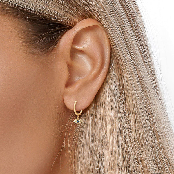 Woman wearing gold crystal eye mini hoop earrings