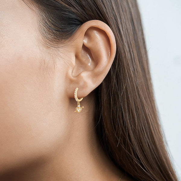 Gold crystal heart drop huggie hoop earrings on woman