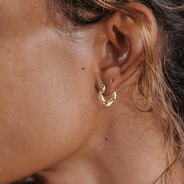 Woman wearing gold curly hoop earrings