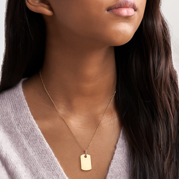 Woman wearing a gold dog tag necklace