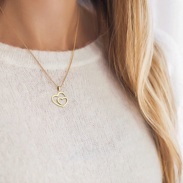 Woman wearing a gold double heart pendant necklace