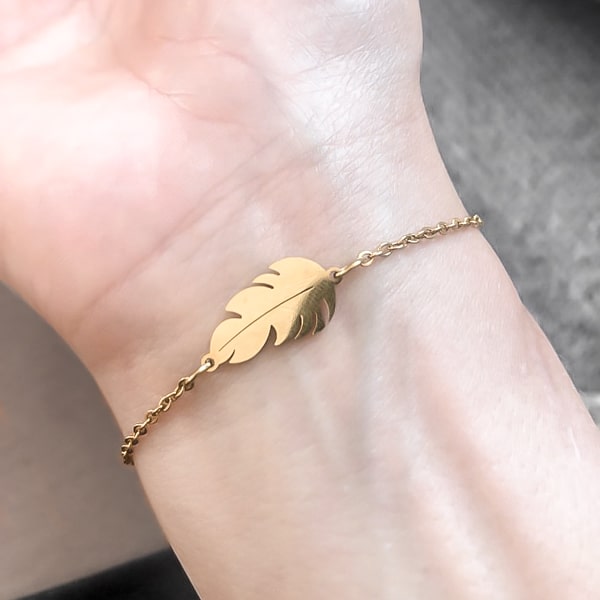 Gold feather bracelet on a woman's wrist