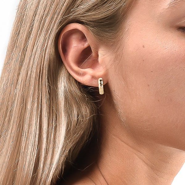 Woman wearing gold hammered mini hoop earrings