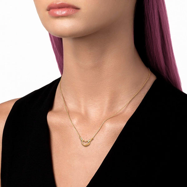 Woman wearing a gold heart hand sign necklace