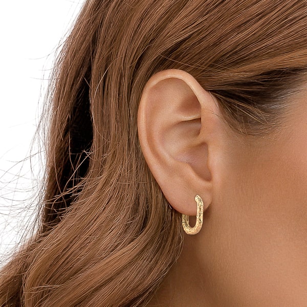 Woman wearing gold irregular oval hoop earrings