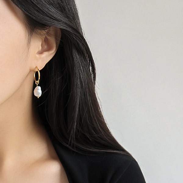 Woman wearing gold large pearl drop hoop earrings