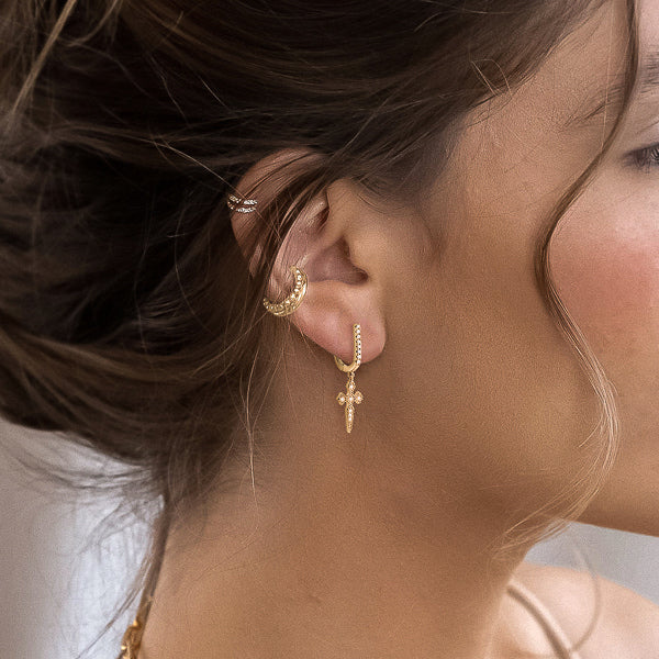 Woman wearing gold medieval cross earrings