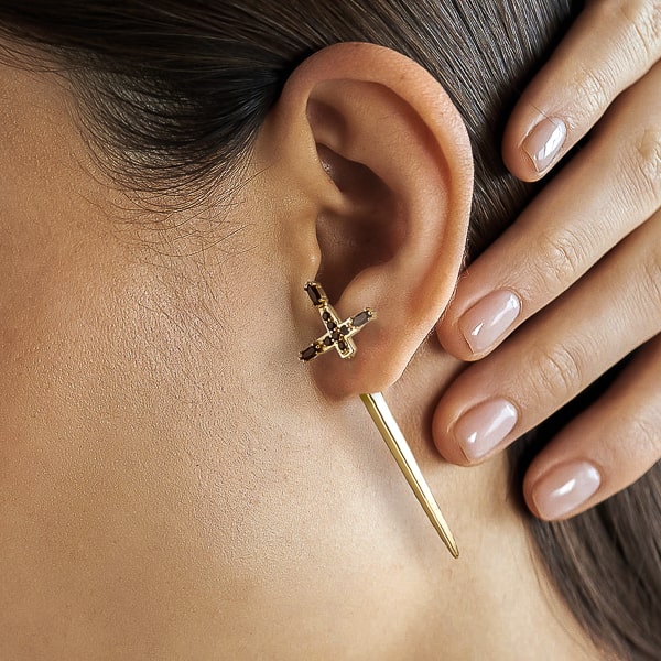 Woman wearing gold medieval sword earrings