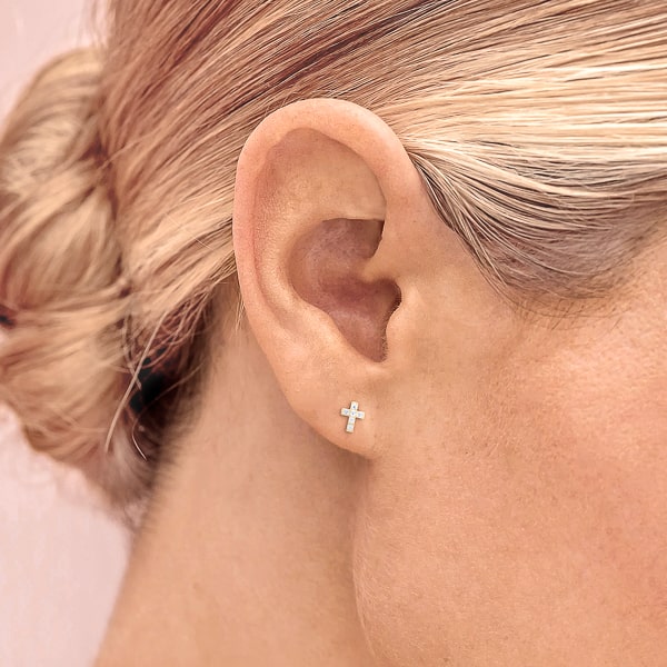 Model wearing gold mini crystal cross stud earrings