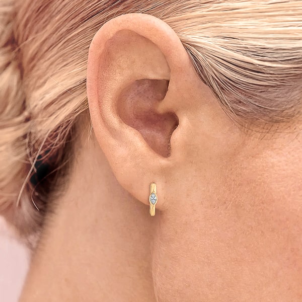 Woman wearing gold mini marquise hoop earrings
