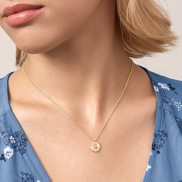 Woman wearing a gold mini snake coin necklace