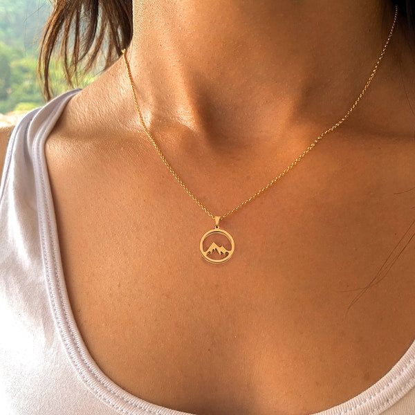 Gold mountain coin pendant necklace on a woman's neck