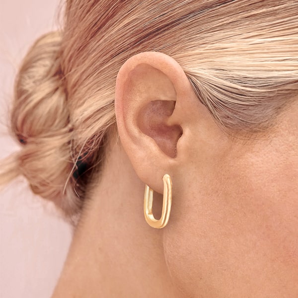 Woman wearing gold oval hoop earrings