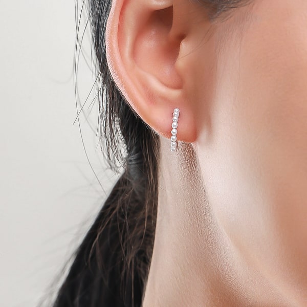 Woman wearing gold pearl mini hoop earrings