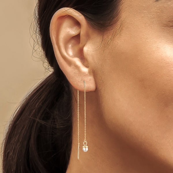Woman wearing gold pearl threader earrings