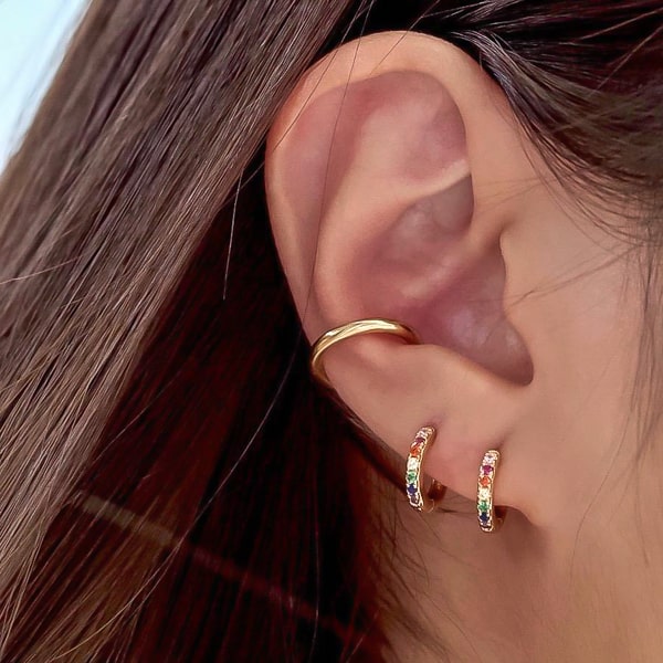 Gold rainbow crystal huggie earrings on woman