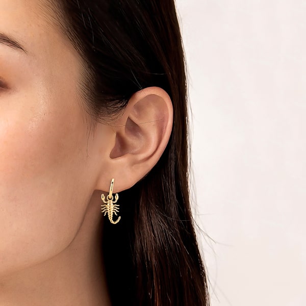 Woman wearing gold scorpion hoop earrings