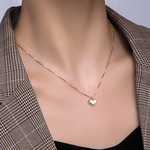 Woman wearing a gold shell heart pendant necklace