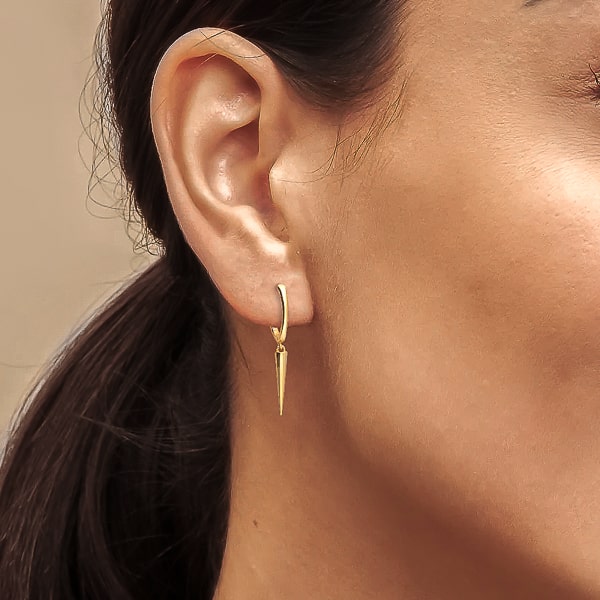 Woman wearing gold single spike hoop earrings