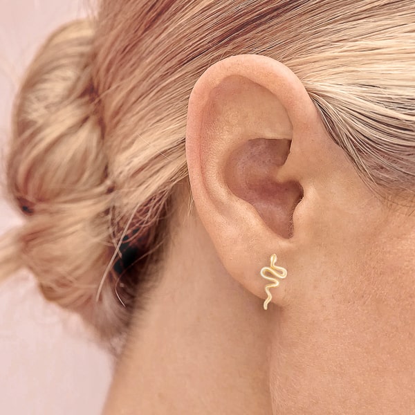 Woman wearing gold snake stud earrings