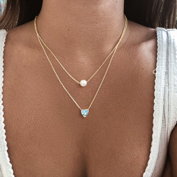 Woman wearing a gold turquoise crystal heart necklace