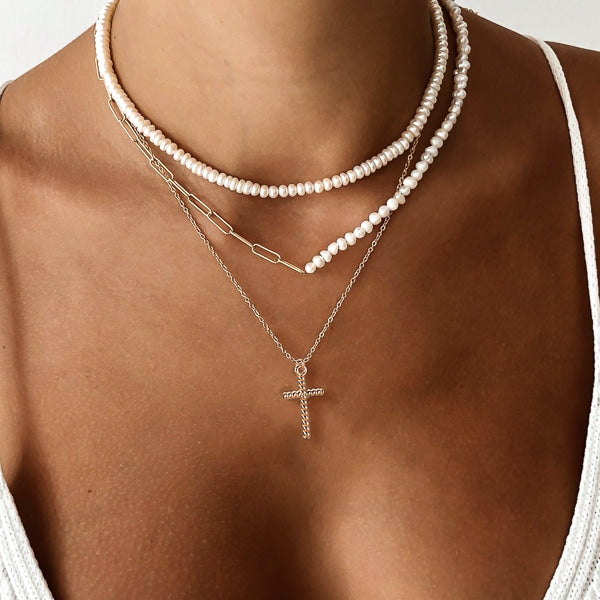 Woman wearing a twisted gold cross pendant necklace