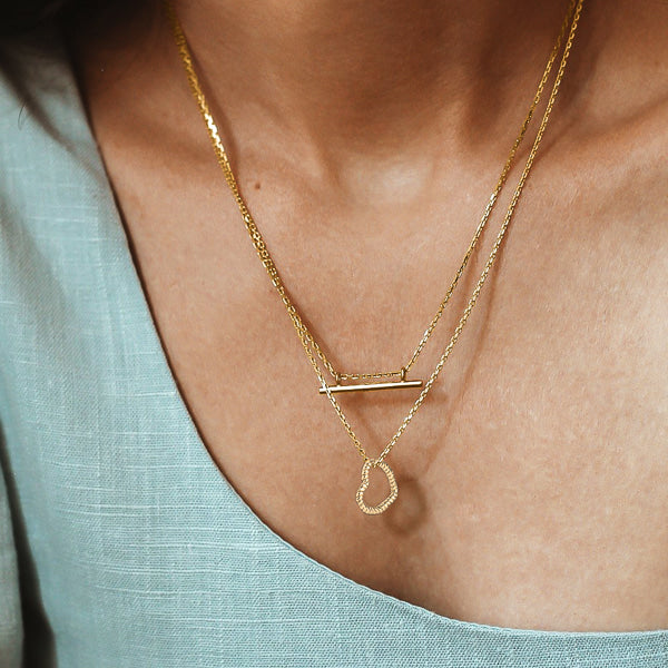 Woman wearing a gold twisted open heart pendant necklace