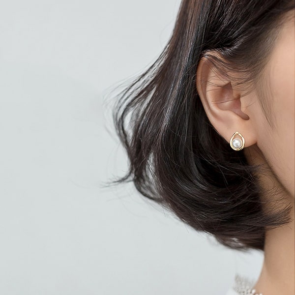 Woman wearing gold waterdrop pearl stud earrings
