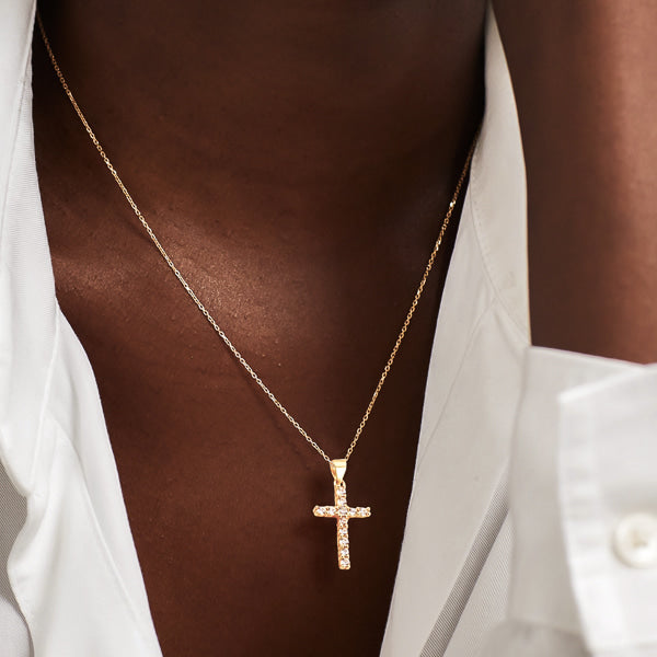 Woman wearing a white crystal cross on a golden necklace