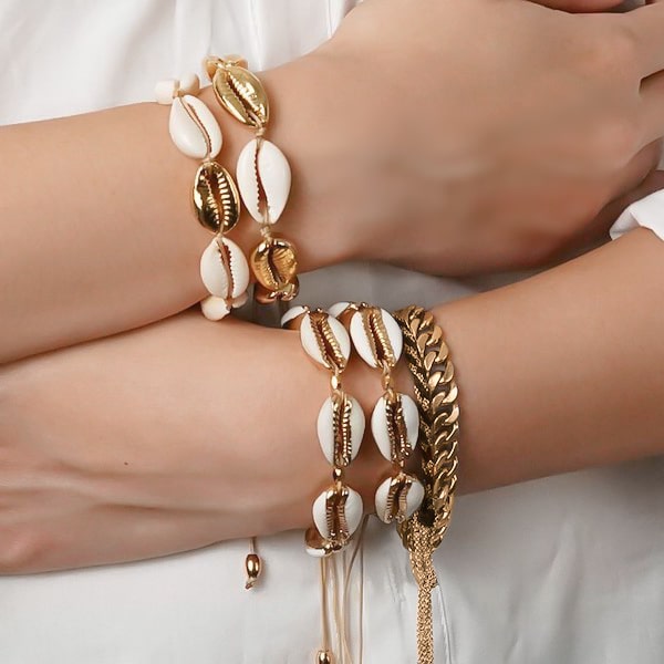 Golden cowrie shell bracelet on a woman's wrist