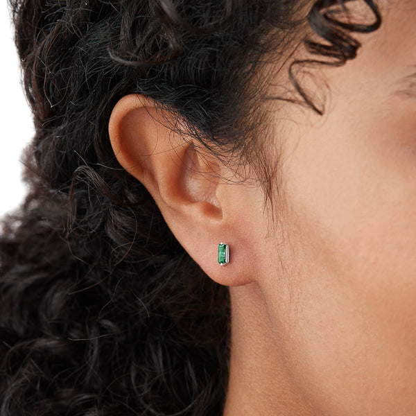 Woman wearing silver and green mini baguette cubic zirconia stud earrings