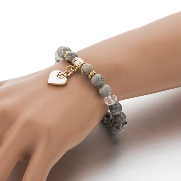 Woman wearing a beaded grey onyx stone bracelet with a gold heart charm