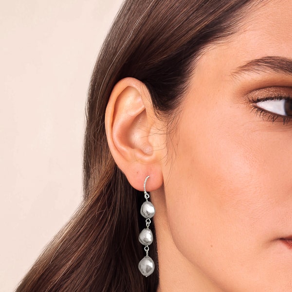 Woman wearing grey triple pearl drop earrings