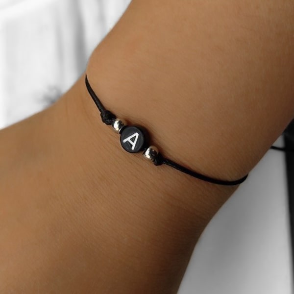 A black initial letter bracelet on a womans wrist