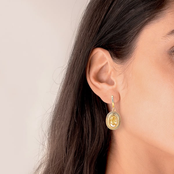 Woman wearing large gold oval stone drop earrings