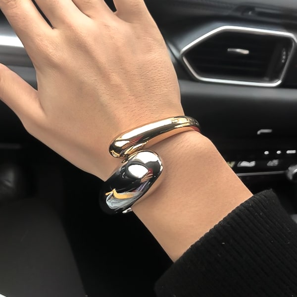 Large gold & silver bangle bracelet on a woman's wrist