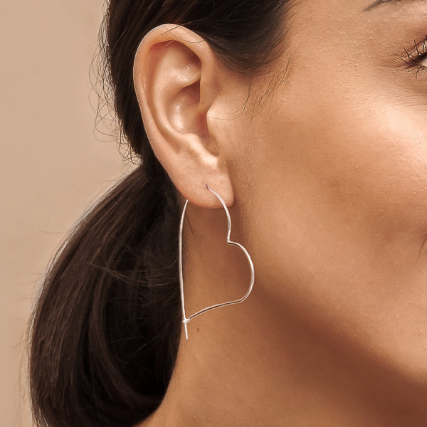 Woman wearing large heart-shaped hoop earrings