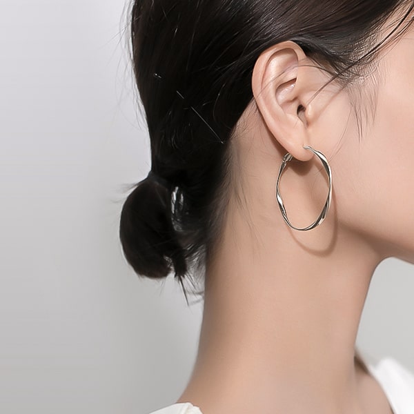 Model wearing large irregular silver hoop earrings