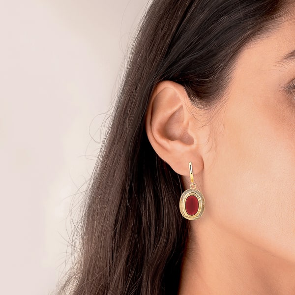 Woman wearing large red oval stone drop earrings