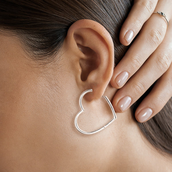 Large silver heart hoop earrings on model