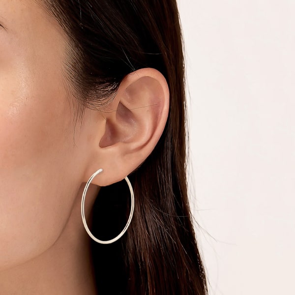 Model wearing large thin silver hoop earrings