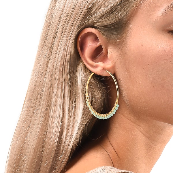 Woman wearing large turquoise bead hoop earrings